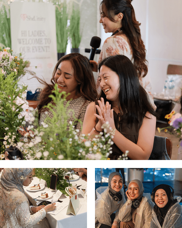 Three women wearing light-colored hijabs stand close together indoors, smiling and holding bouquets of pink and white flowers wrapped in brown paper.